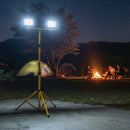 Camping scene at night with a portable light stand illuminating the area.